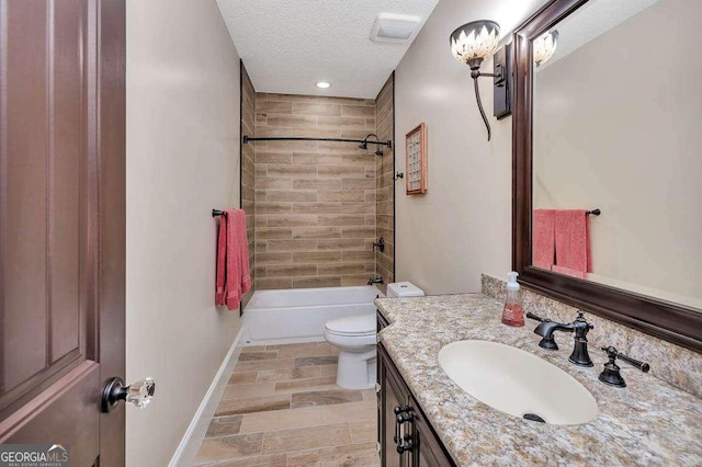 full bathroom featuring a textured ceiling, vanity, tiled shower / bath combo, and toilet