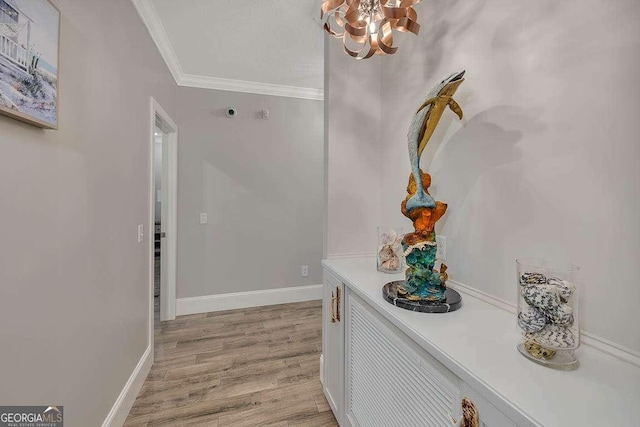 corridor with light wood-type flooring, an inviting chandelier, and crown molding