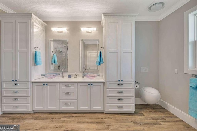 bathroom featuring a textured ceiling, vanity, wood-type flooring, and crown molding