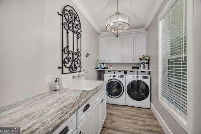 clothes washing area featuring hardwood / wood-style floors, cabinets, sink, crown molding, and washer and dryer