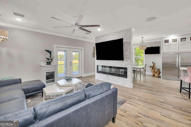 living room featuring french doors, crown molding, ceiling fan, a fireplace, and light hardwood / wood-style floors