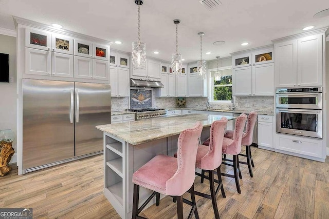 kitchen with white cabinetry, crown molding, a kitchen island, and stainless steel appliances