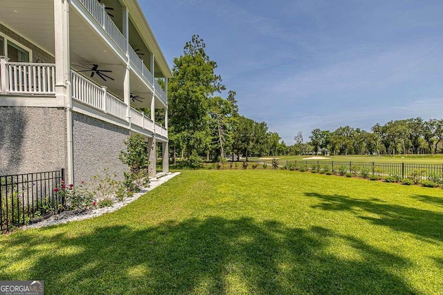 view of yard with ceiling fan and a balcony