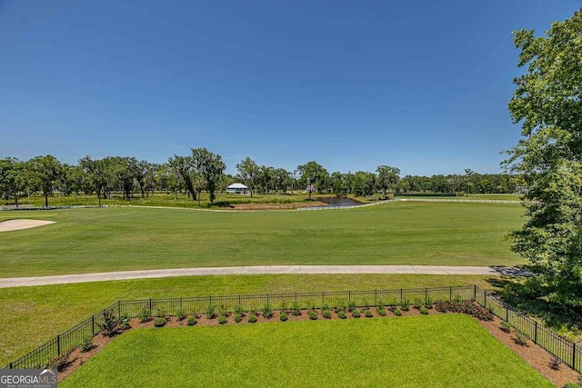 surrounding community with a water view and a lawn