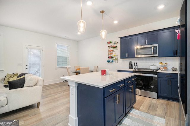 kitchen featuring hanging light fixtures, stainless steel appliances, light hardwood / wood-style flooring, blue cabinets, and decorative backsplash