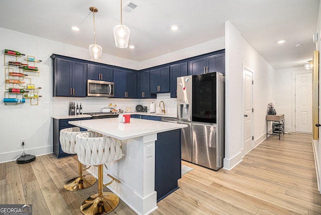 kitchen featuring pendant lighting, a kitchen breakfast bar, light hardwood / wood-style flooring, decorative backsplash, and appliances with stainless steel finishes