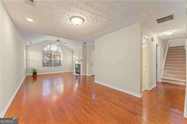 unfurnished living room featuring hardwood / wood-style floors, ceiling fan, lofted ceiling, and a textured ceiling