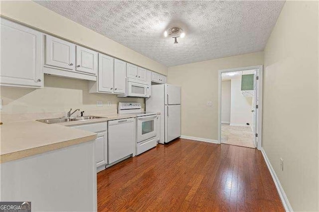 kitchen featuring a textured ceiling, white appliances, sink, wood-type flooring, and white cabinets