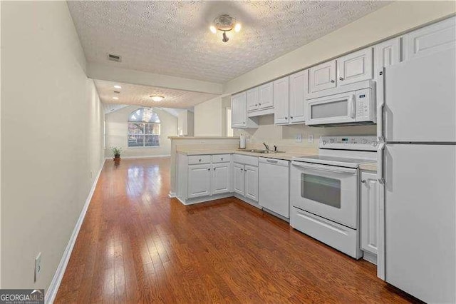 kitchen with a textured ceiling, white appliances, sink, hardwood / wood-style floors, and white cabinetry