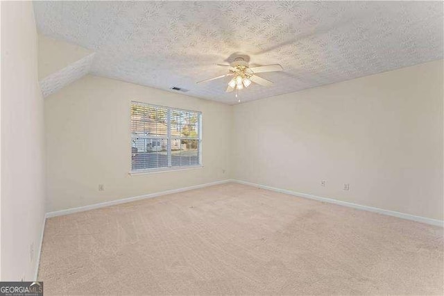 unfurnished room with ceiling fan, lofted ceiling, a textured ceiling, and light carpet