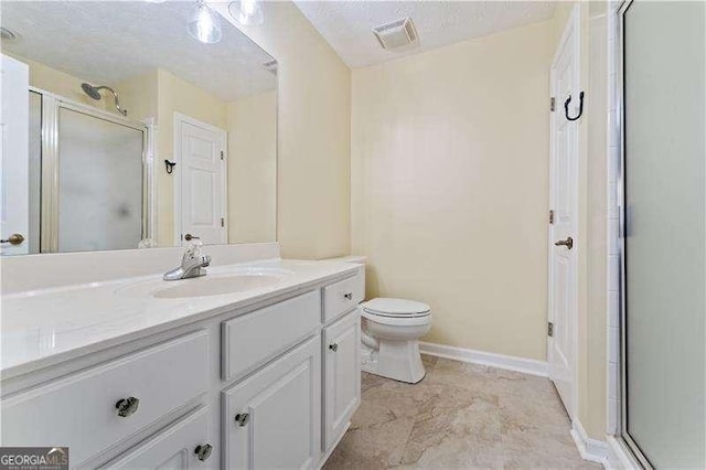 bathroom with a textured ceiling, vanity, an enclosed shower, and toilet