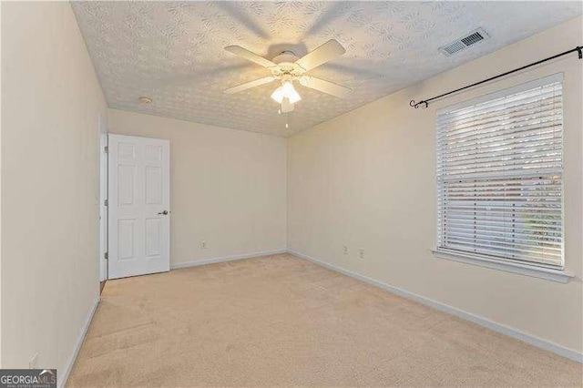 carpeted empty room featuring ceiling fan and a textured ceiling