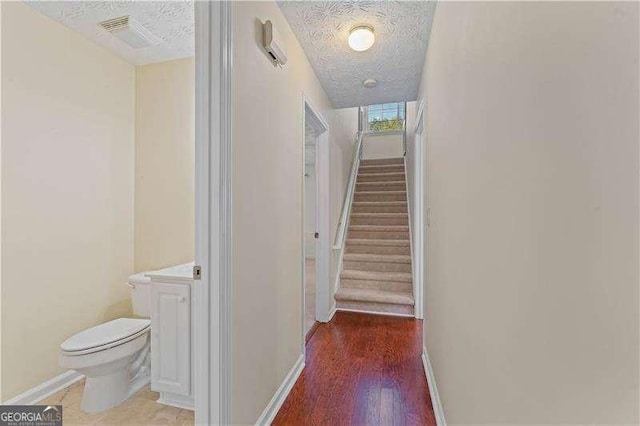 stairs featuring hardwood / wood-style floors and a textured ceiling