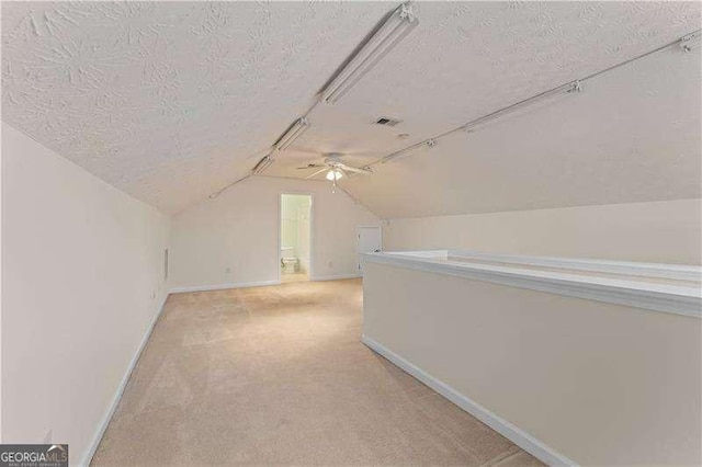 bonus room with vaulted ceiling, light carpet, and a textured ceiling