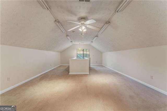 bonus room featuring vaulted ceiling, light carpet, ceiling fan, and a textured ceiling