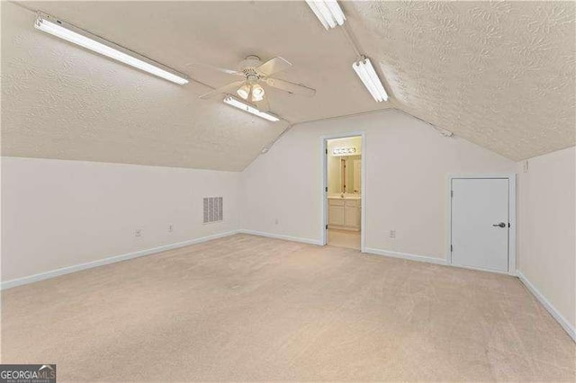 bonus room featuring ceiling fan, light colored carpet, lofted ceiling, and a textured ceiling