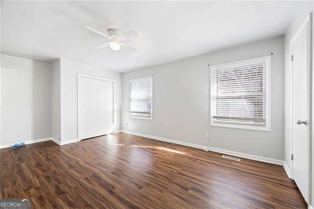 unfurnished bedroom featuring multiple windows, ceiling fan, and dark wood-type flooring