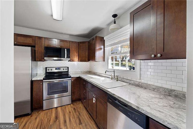 kitchen featuring sink, decorative backsplash, appliances with stainless steel finishes, dark brown cabinets, and wood-type flooring