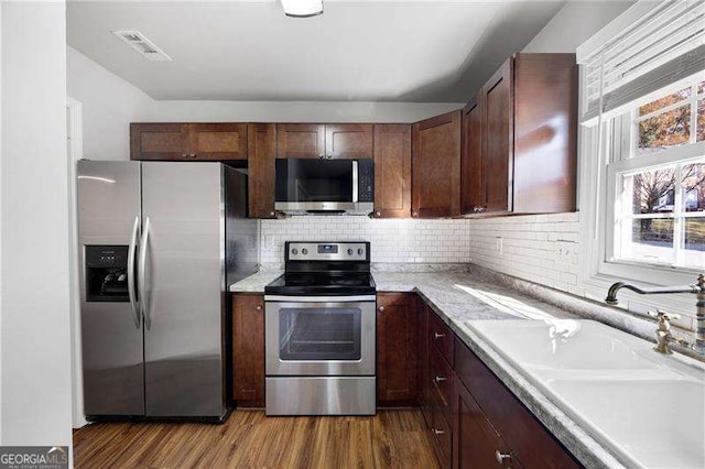 kitchen with hardwood / wood-style floors, tasteful backsplash, sink, and stainless steel appliances