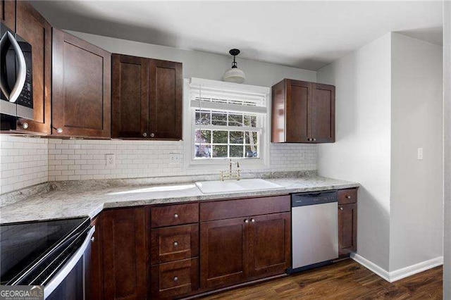 kitchen with light stone countertops, sink, stainless steel appliances, dark hardwood / wood-style floors, and decorative backsplash