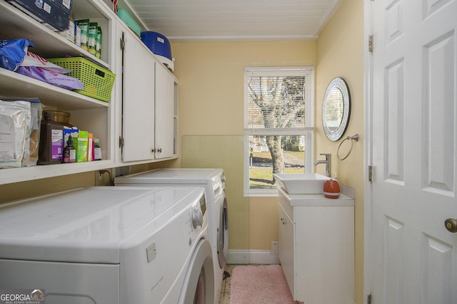 clothes washing area featuring washer and clothes dryer, wooden ceiling, sink, and cabinets