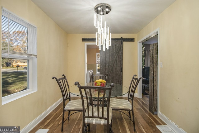 dining space with a chandelier, dark hardwood / wood-style flooring, and a barn door