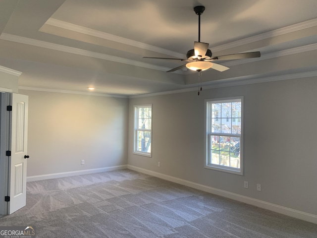 carpeted empty room featuring crown molding, ceiling fan, a tray ceiling, and a wealth of natural light