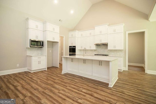 kitchen featuring high vaulted ceiling, white cabinetry, an island with sink, and appliances with stainless steel finishes