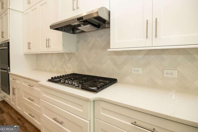 kitchen with stainless steel gas cooktop, tasteful backsplash, light stone counters, dark hardwood / wood-style flooring, and double oven