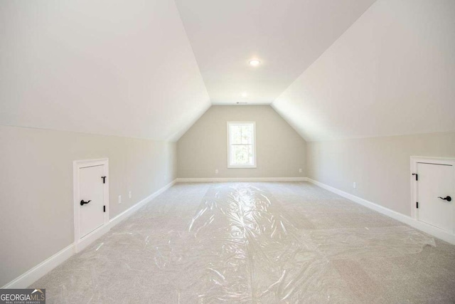 additional living space with light carpet and vaulted ceiling