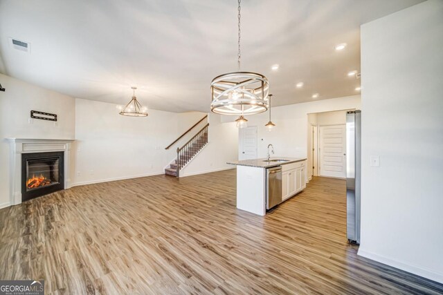 kitchen featuring sink, hanging light fixtures, light hardwood / wood-style floors, white cabinetry, and stainless steel appliances