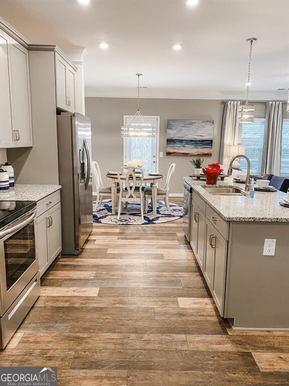 kitchen featuring sink, hanging light fixtures, gray cabinets, light wood-type flooring, and appliances with stainless steel finishes