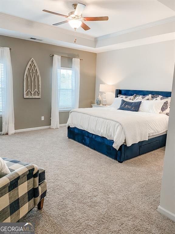 carpeted bedroom with ceiling fan and ornamental molding