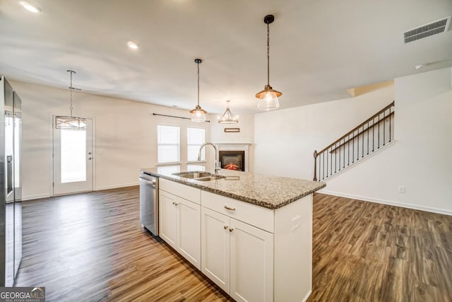 kitchen featuring appliances with stainless steel finishes, dark hardwood / wood-style floors, light stone counters, and sink