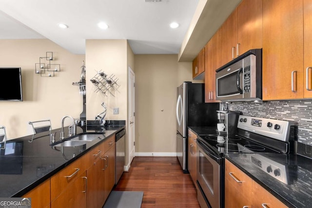 kitchen featuring sink, stainless steel appliances, dark hardwood / wood-style floors, backsplash, and dark stone countertops