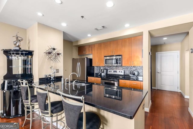 kitchen with sink, stainless steel appliances, a kitchen breakfast bar, dark hardwood / wood-style floors, and kitchen peninsula