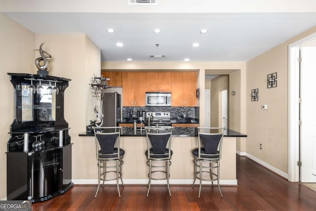 kitchen featuring dark hardwood / wood-style floors, a kitchen bar, and stainless steel appliances