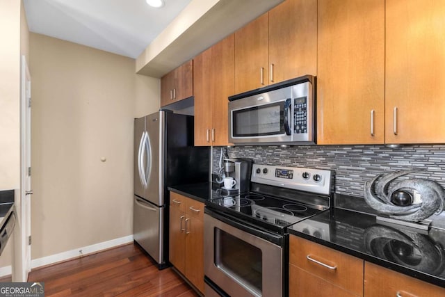 kitchen featuring backsplash, dark stone counters, dark hardwood / wood-style floors, and appliances with stainless steel finishes