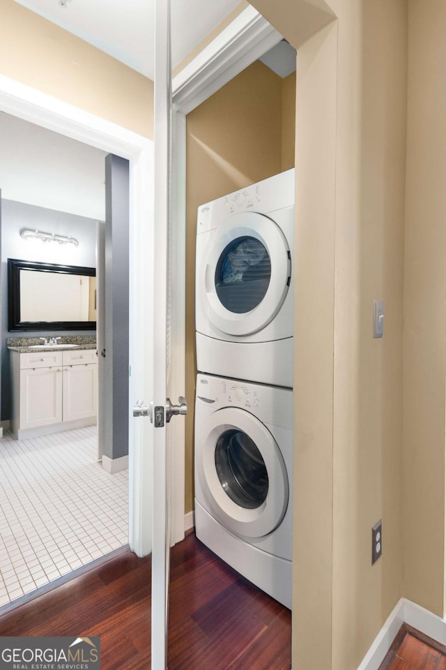 washroom with stacked washer / drying machine and dark wood-type flooring