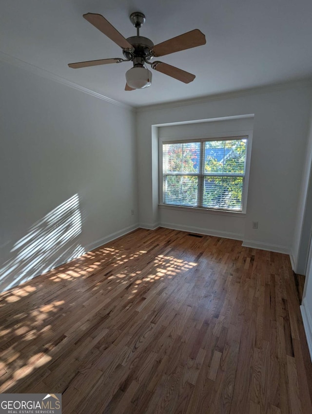 empty room featuring ceiling fan, dark wood-type flooring, and ornamental molding