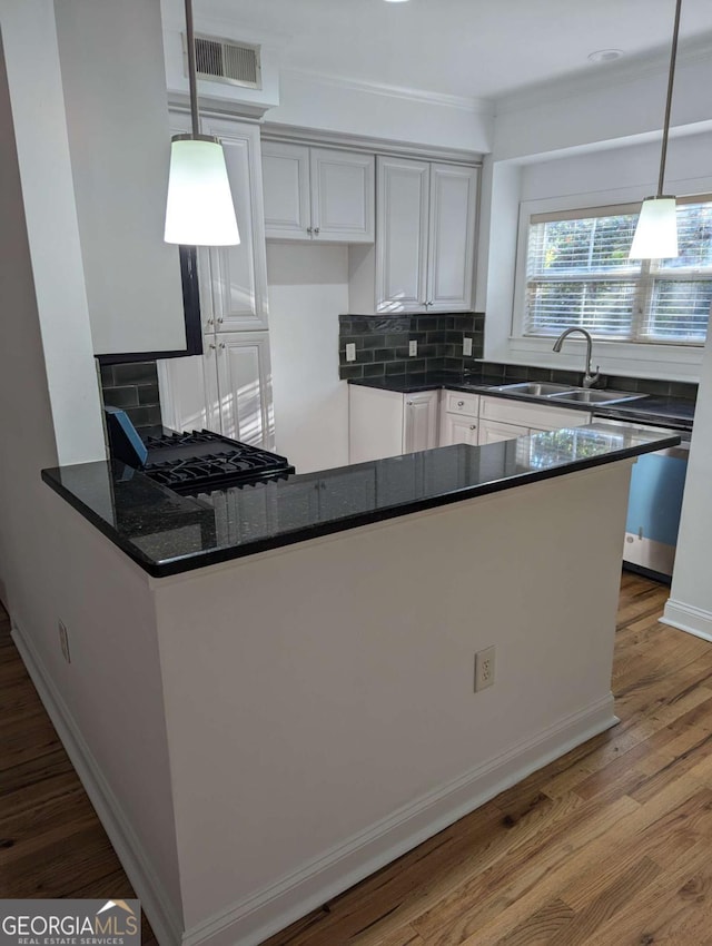 kitchen featuring white cabinets, sink, wood-type flooring, and hanging light fixtures