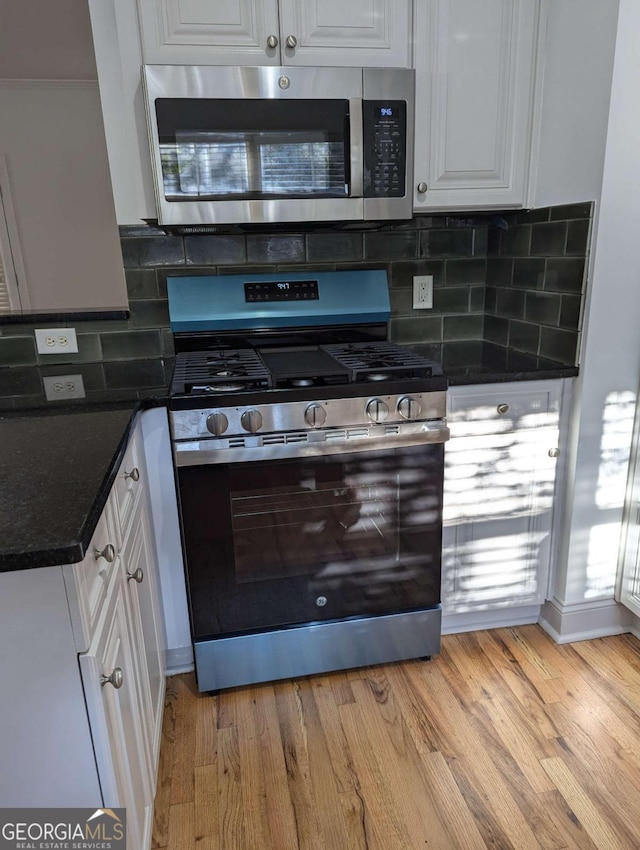 kitchen featuring appliances with stainless steel finishes, light wood-type flooring, white cabinetry, and backsplash