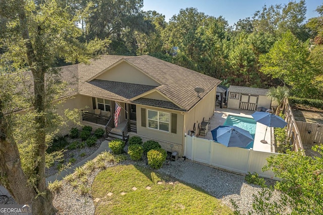 view of front of home featuring a storage shed, a fenced in pool, and a patio