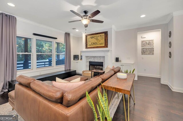 living room featuring ceiling fan, dark hardwood / wood-style floors, crown molding, and a tiled fireplace