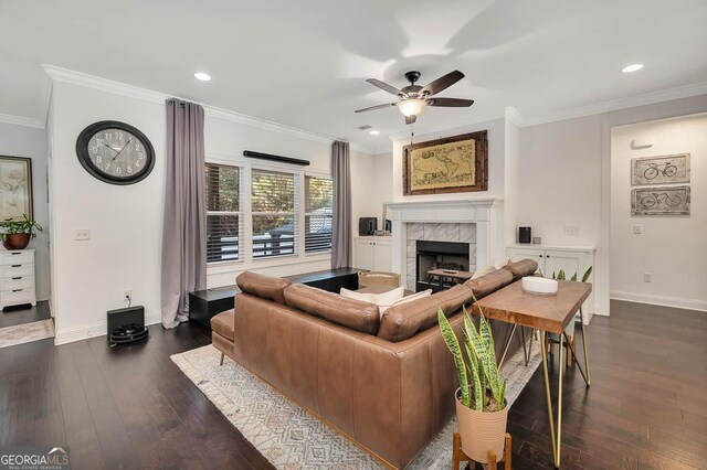 living room featuring ceiling fan, dark hardwood / wood-style flooring, crown molding, and a tiled fireplace