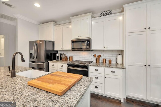 kitchen with decorative backsplash, appliances with stainless steel finishes, white cabinetry, and sink