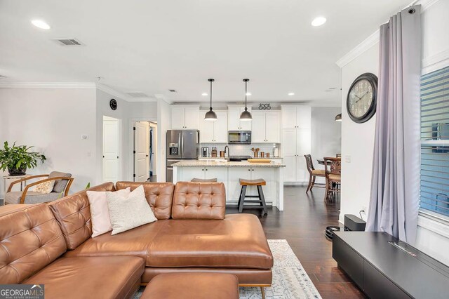 living room with crown molding, dark hardwood / wood-style flooring, and sink