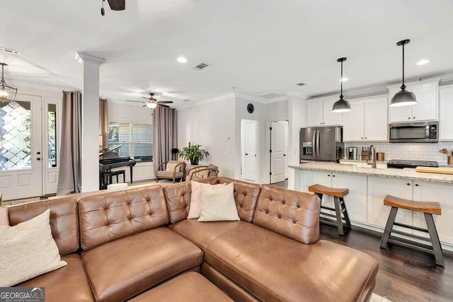 living room featuring dark hardwood / wood-style flooring, ornate columns, ceiling fan, and ornamental molding