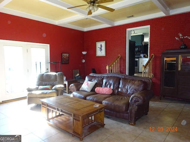 tiled living room with beam ceiling, ceiling fan, coffered ceiling, and brick wall