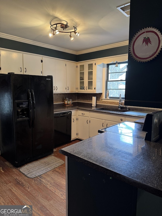 kitchen with white cabinetry, sink, backsplash, black appliances, and hardwood / wood-style flooring